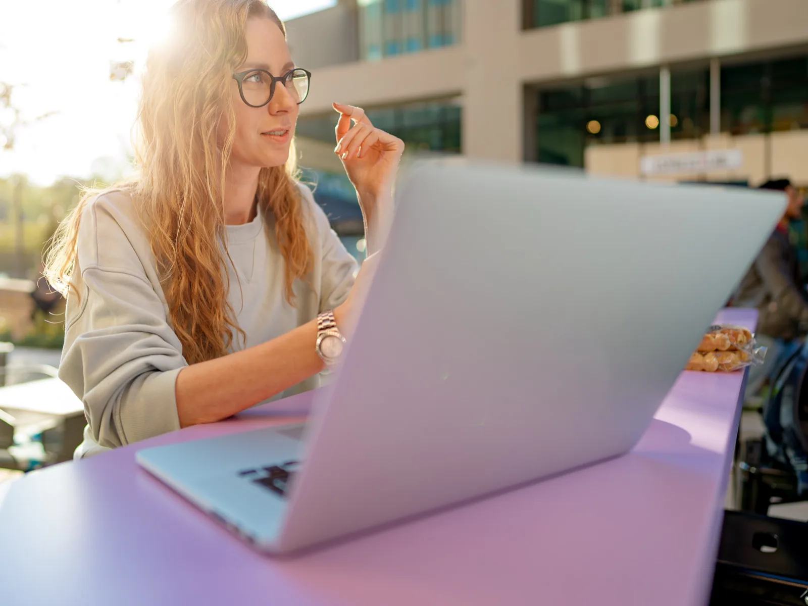 Frau mit Laptop an einem Tisch im Freien
