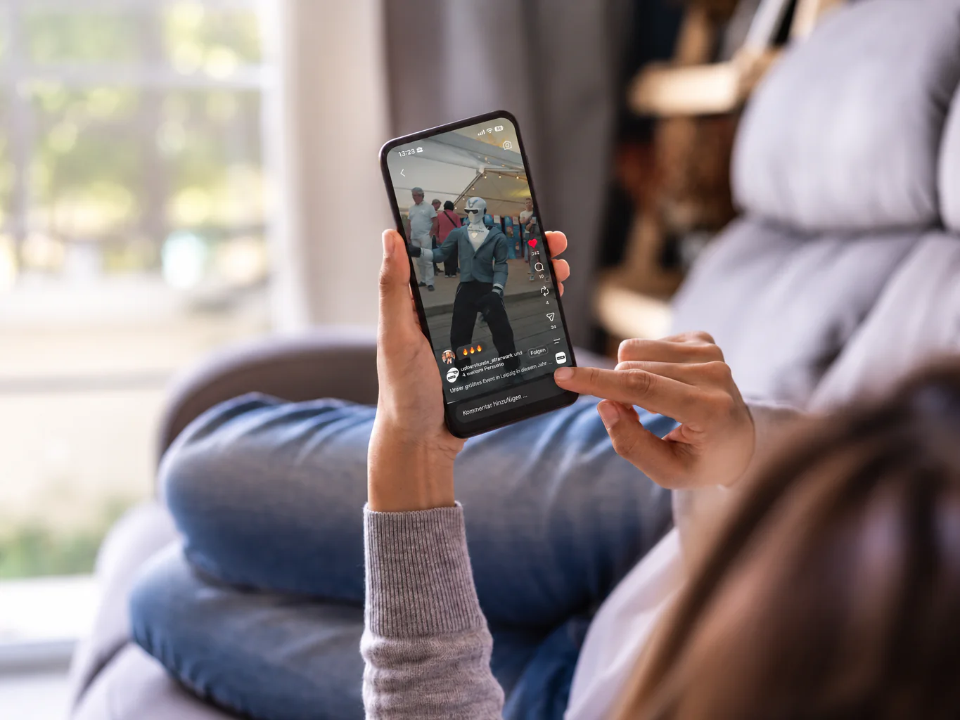 Person auf dem Sofa, die auf dem Smartphone ein Video ansieht